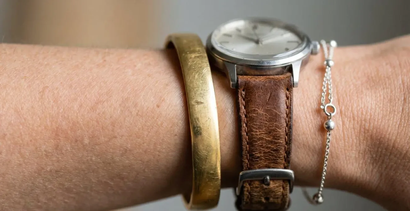 Handgelenk mit elegantem Mix aus Schmuckstücken verschiedener Stile auf minimalistischem Hintergrund