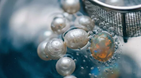 Nahaufnahme eines Ultraschallbads mit empfindlichen Edelsteinen und Wasserbewegung