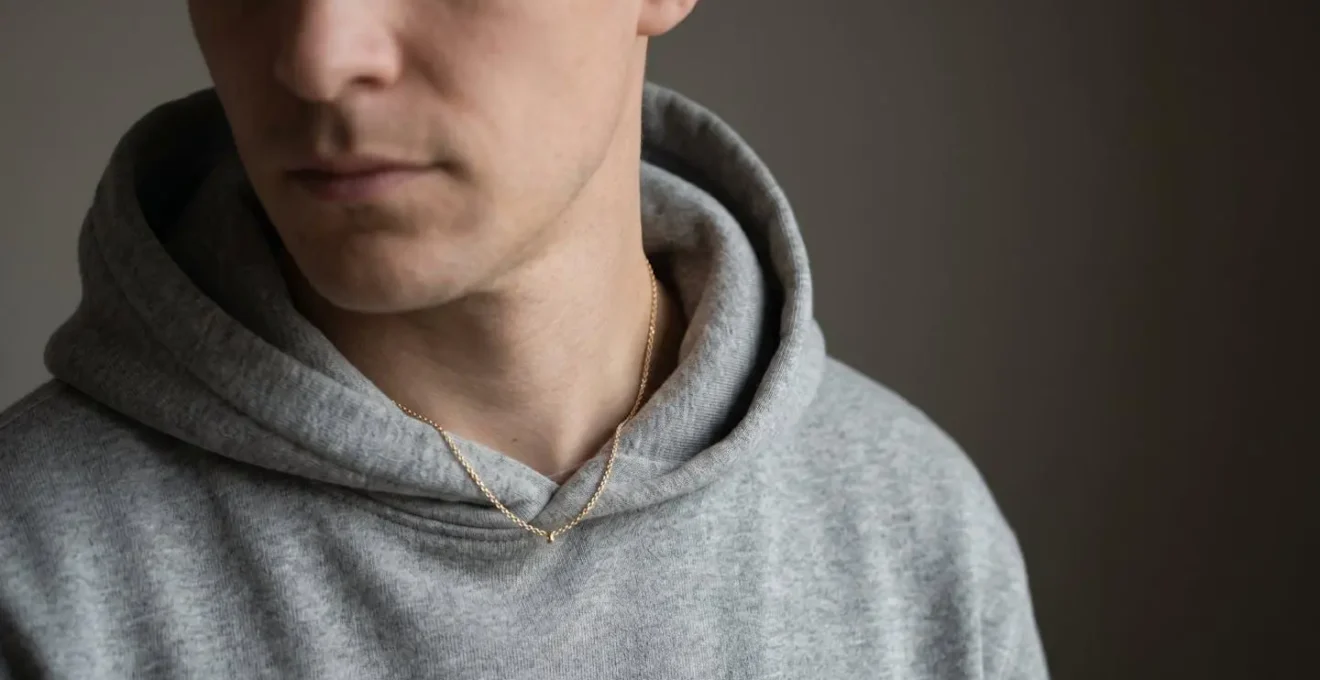 Dezente Goldkette unter dem Hoodie halb verborgen, nur teilweise sichtbar am Hals